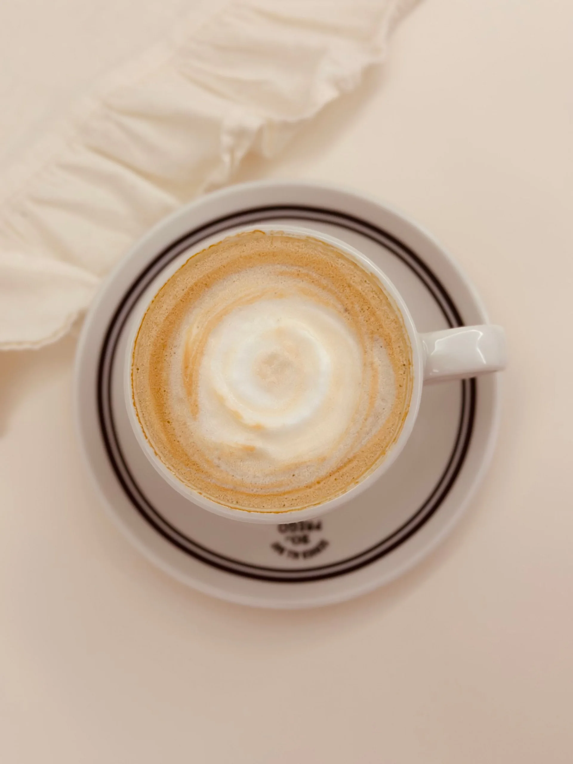 Milchkaffee mit Schaum in einer weißen Tasse, von oben – Stimmungsbild, kein nachgewiesenes PINE-NUT-LATTE-Rezept